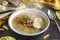 Healthy and warming winter soup with rice, carrot, chickpeas, chicken, ham and boiled egg over rustic wooden table background