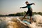 healthy wet man energetically balancing on wave on wakesurf board.