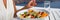 Healthy woman eating salad banner crop of diet meal at restaurant table. Closeup of plate on outdoor cafe terrace plate