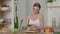 Healthy woman peeling cucumber while standing in kitchen