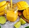 Healthy Yellow Banana Mango Smoothie with slices of Lime, mint and ice