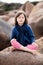 Healthy yoga child with eyes closed sitting in granite stone