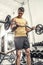 Healthy young man practicing biceps lifting a curl bar.