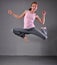 Healthy young muscular teenage girl skipping and dancing in studio. Child exercising with jumping on grey background.