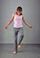 Healthy young muscular teenage girl skipping rope in studio. Child exercising with jumping high on grey background.