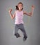 Healthy young muscular teenage girl skipping rope in studio. Child exercising with jumping high on grey background.