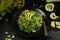 Healthy Zucchini Noodles with Basil Pesto, Beans, Brussels Sprouts and Avocado - served on a black background