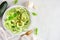 Healthy zucchini pasta topped with garlic and basil, top view table scene over white marble