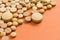 Heap of assorted beige capsules on orange table.
