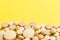 Heap of assorted beige capsules on yellow background.