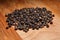 Heap of black peppercorns on wooden beech cutting board