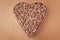 Heap of buckwheat grains on brown background. Heart shaped. Bunch of seeds. Carbohydrate diet concept