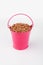 Heap buckwheat grains in pink bucket on white background