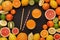 Heap of citruses and juice glass on black background, top view