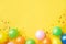 Heap of colorful balloons, confetti and candies on yellow table top view. Birthday party background. Festive greeting card