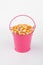 Heap corn grains in pink bucket on white background