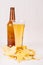 Heap different crispy golden snacks and beer in glass, brown bottle on soft white wood background.