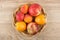 Heap of different ripe fruits in wicker basket on table