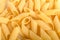 Heap of dried mezze penne rigate Italian pasta ready to be cooked, isolated on a white table, top view