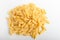 Heap of dried mezze penne rigate Italian pasta ready to be cooked, isolated on a white table, top view or flat lay of healthy food