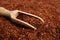 Heap of dry rooibos tea leaves with wooden scoop, closeup view