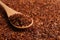 Heap of dry rooibos tea leaves with wooden spoon, closeup. Space for text