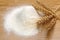 Heap of flour and wheat ears on wooden plate