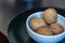 Heap, four whole walnuts in a round-shaped brown shell lie in a small white platter in black plate on table blurred bokeh