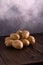 Heap of fresh potatoes on rustic wooden surface and slate textured background. Organic food, carbs, tubers.