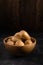 Heap of fresh potatoes in a wooden bowl on dark textured surface. Organic food, carbs, tubers.