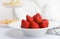 Heap of fresh strawberries in ceramic bowl on rustic white background