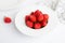 Heap of fresh strawberries in ceramic bowl on rustic white background