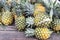 Heap of freshly harvested organic pineapple on wooden surface