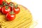 Heap fusilli bucati lunghi italian pasta and Fresh Red ripe tomatoes on a green branch laying on wooden beech board. Isolated on