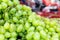 A heap of green grapes at market. Blurry market background.