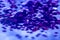 Heap of large deep purple sequins on a reflective surface, texture for wallpaper or background