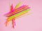 Heap of multicolored plastic cocktail tubes on a pastel pink background. Drinking straws of bright neon colors. Flat lay