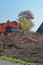 Heap of old bricks and hydraulic bulldozer excavator arm in background