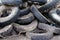 Heap of old muddy tires, junk yard of used car wheels.