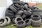 Heap of old used black car tires on junkyard