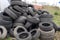 Heap of old used black car tires on junkyard