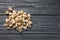 Heap of organic pistachio nuts on wooden table, top view.