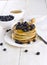 Heap of pancakes watered with honey and blueberry on a white woo