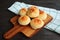 Heap of Pao de Queijo or Brazilian Cheese Breads on Wooden Breadboard