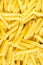 Heap Pile of Uncooked Italian Penne Pasta. Bright Vibrant Yellow Color. Top View. Food Background Pattern.