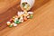 Heap of pills near the opened container on wooden desk