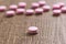 Heap of pink capsules on wooden background. One pill is apart, i