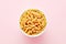 Heap of pipette rigate pasta in a white bowl on pink background