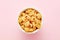 Heap of pipette rigate pasta in a white bowl on pink background