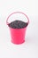 Heap poppy grains in pink bucket on white background